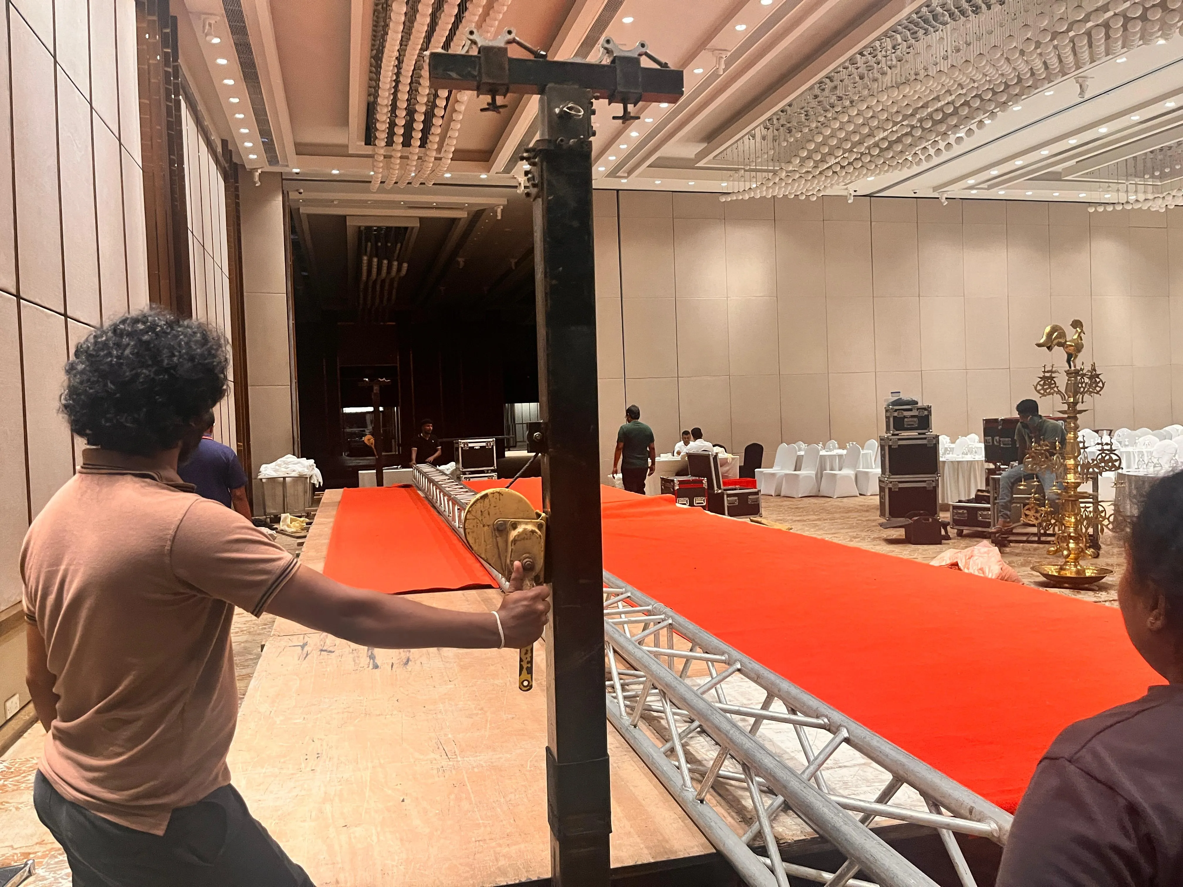 Crew raising a lighting truss with a chain hoist