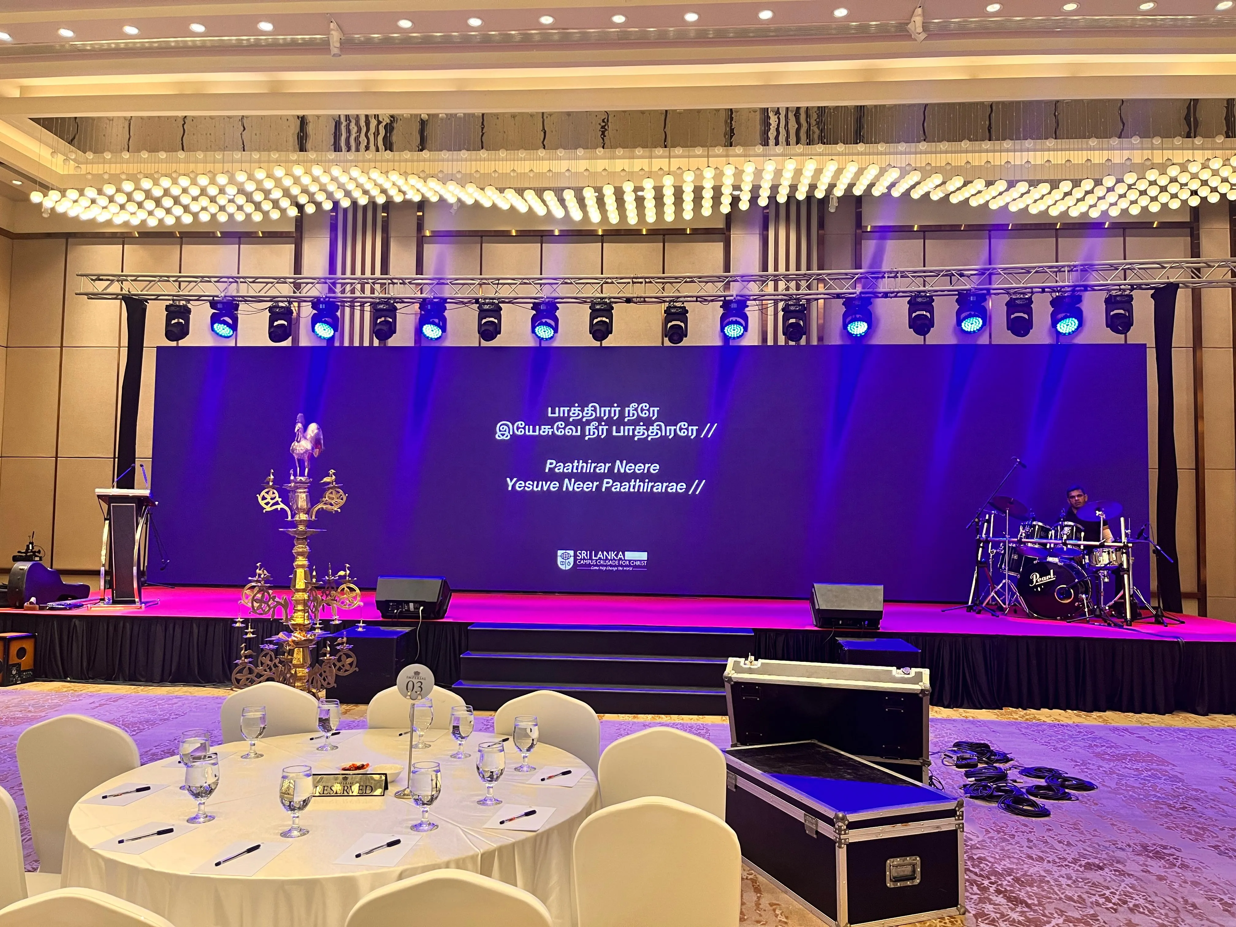 Drummer performing under purple stage lighting