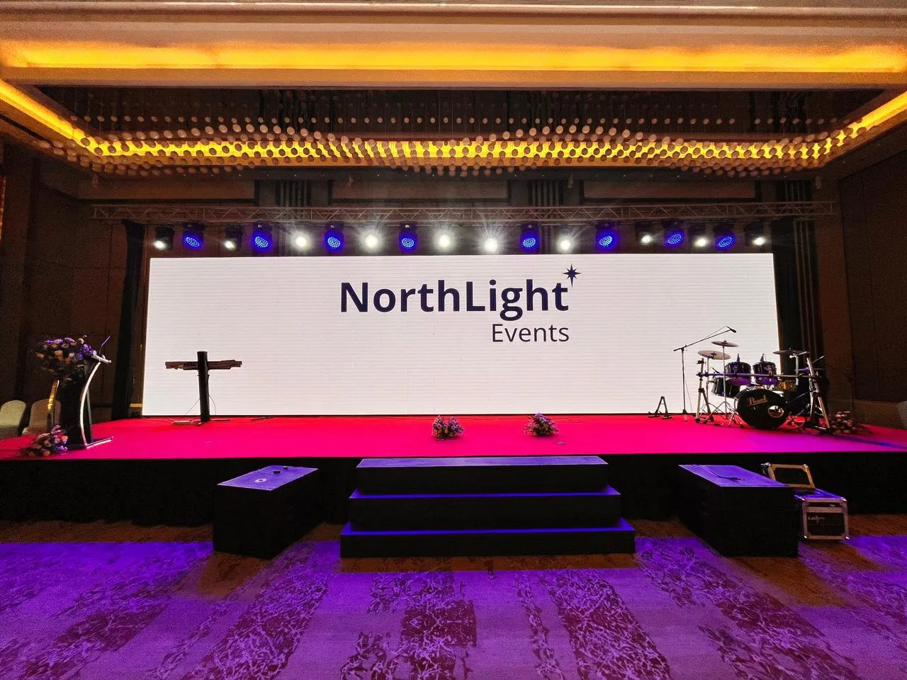 Attendees dancing at a celebration in front of an LED screen