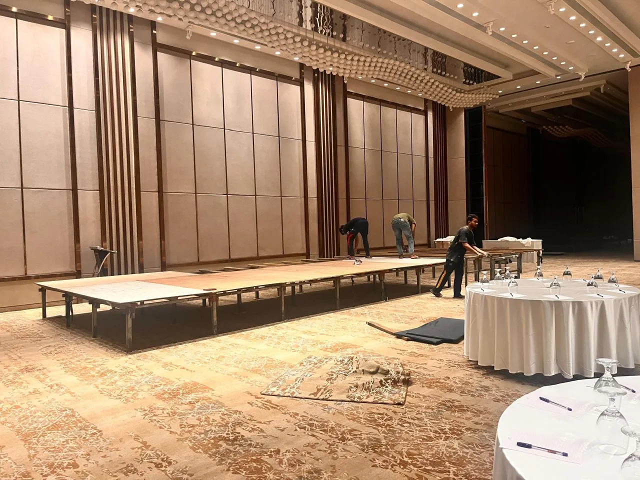 Crew assembling a long stage platform with acoustic treatment